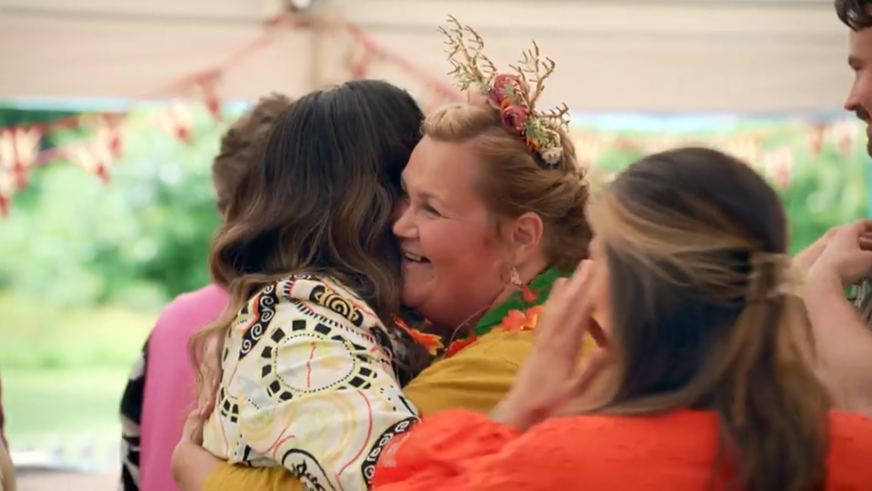 a group of people are hugging each other and one woman is wearing a reindeer headband .