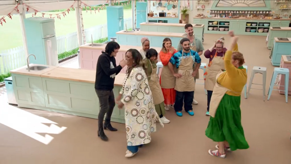 a group of people in aprons are dancing in a kitchen