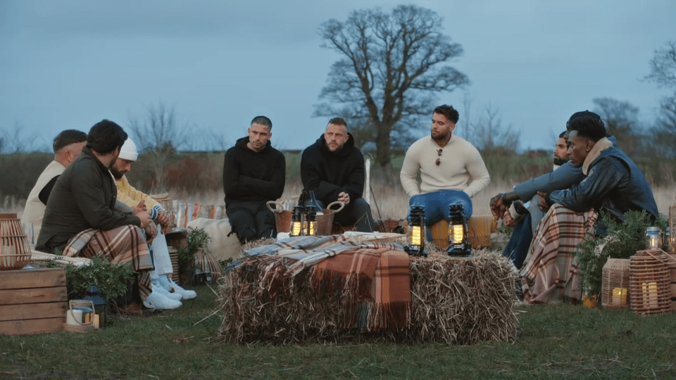 a group of men sit around a hay bale with lanterns on it