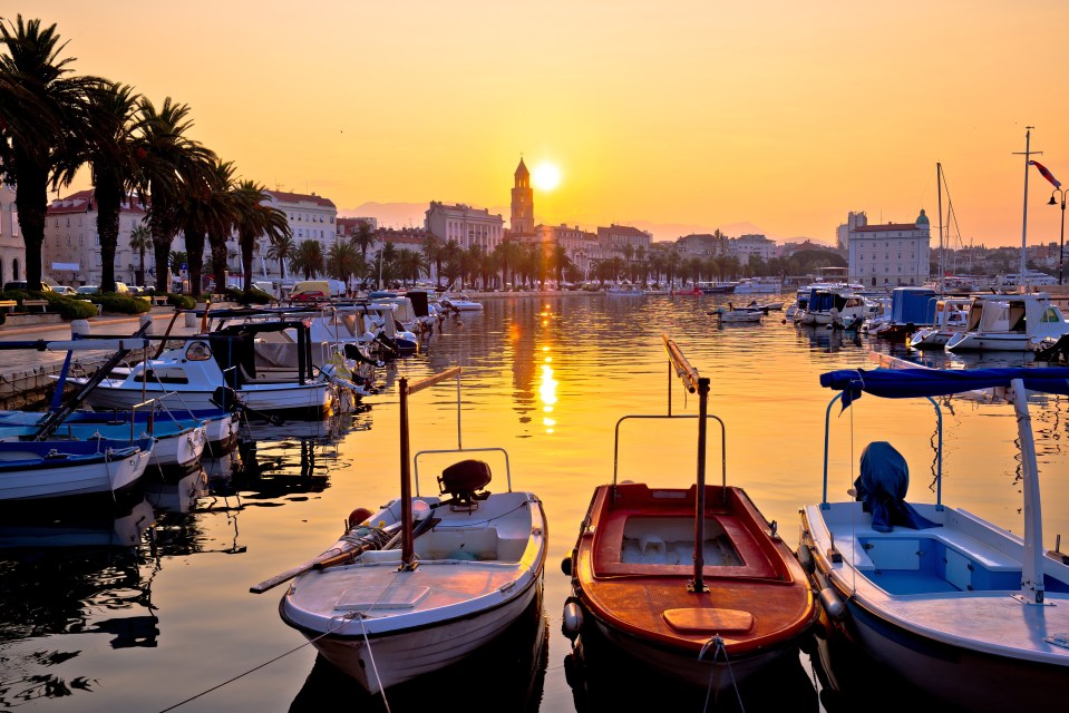 a row of boats are docked in a harbor at sunset