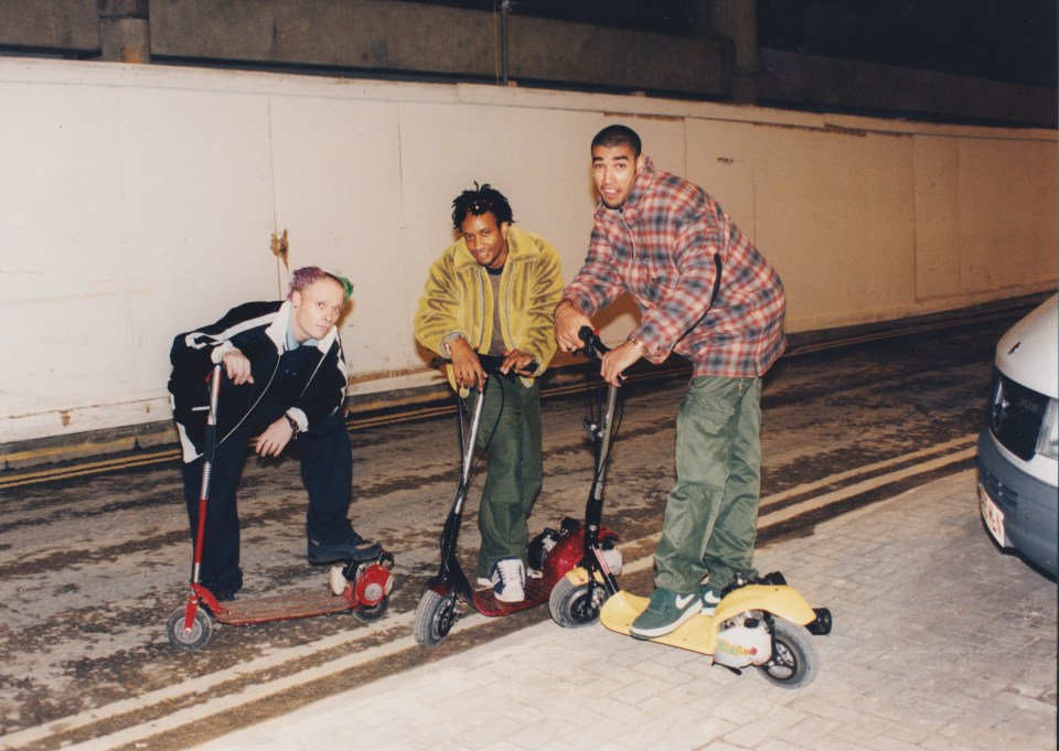 three men are riding scooters one of which has the word nike on it