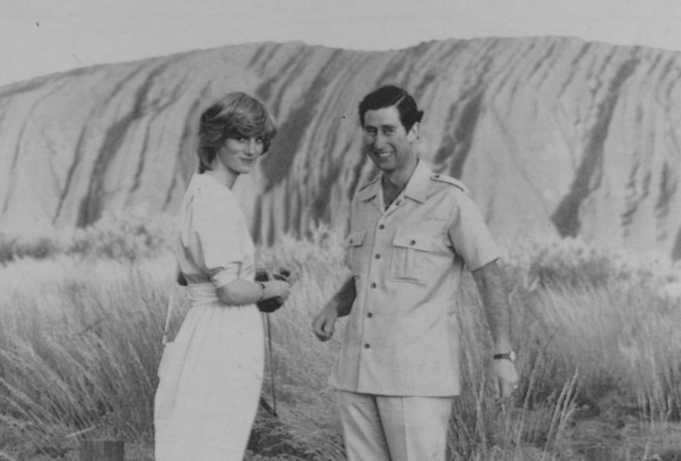 a black and white photo of a man and woman standing in front of a mountain