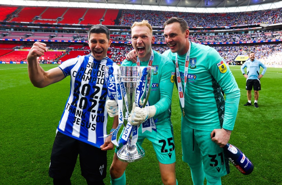 three soccer players holding a trophy with one wearing a shirt that says thank you jesus