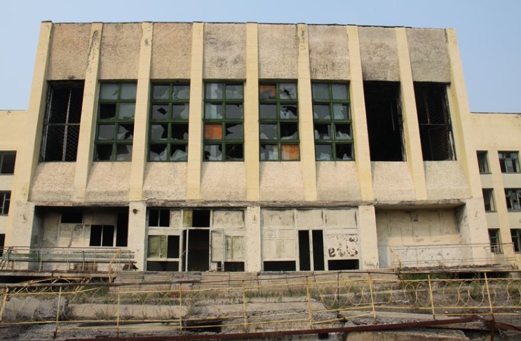 a building with broken windows and a fence around it