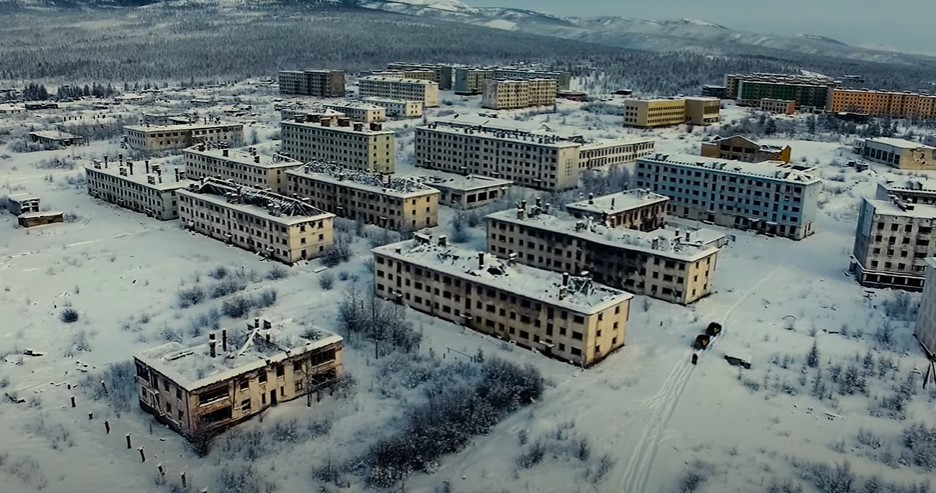 an aerial view of a snowy city with mountains in the background