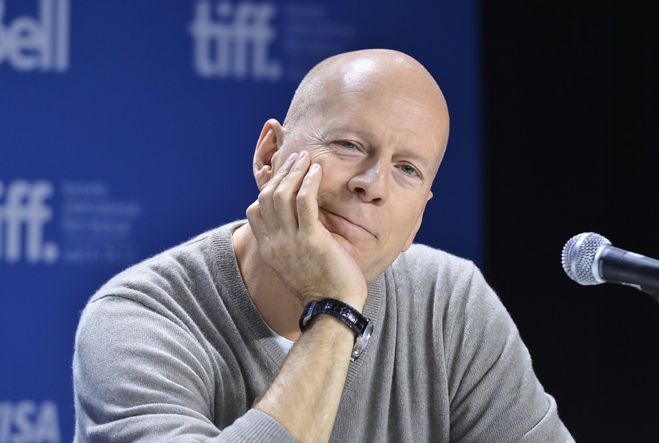 a bald man sitting in front of a tiff sign