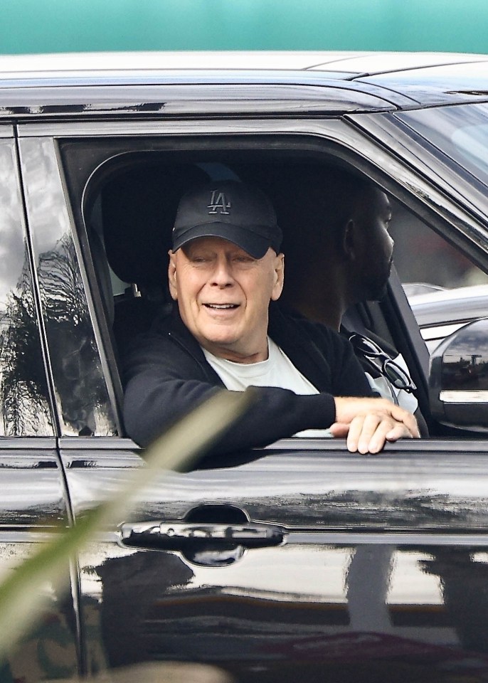 a man wearing a la hat sits in a car