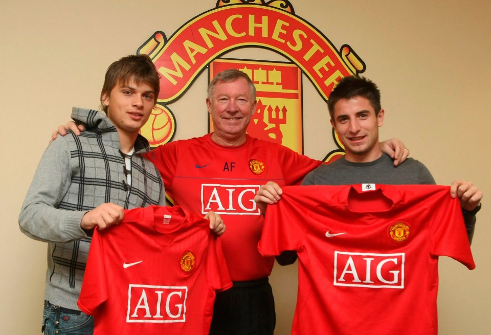 three men holding up red aig shirts in front of a manchester logo