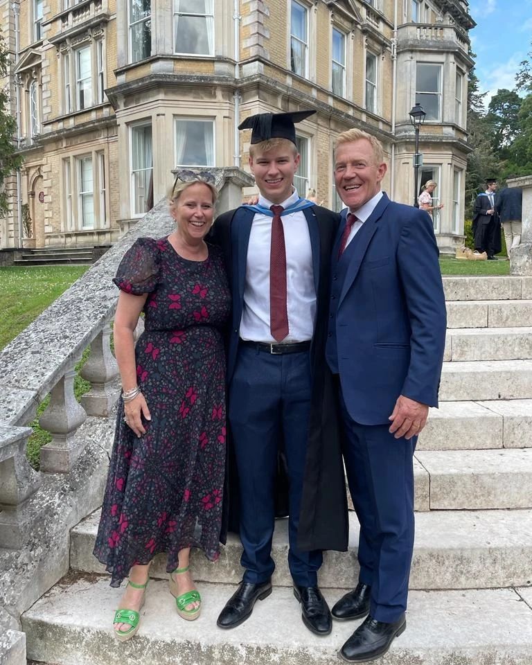 a man in a graduation cap and gown poses with his parents