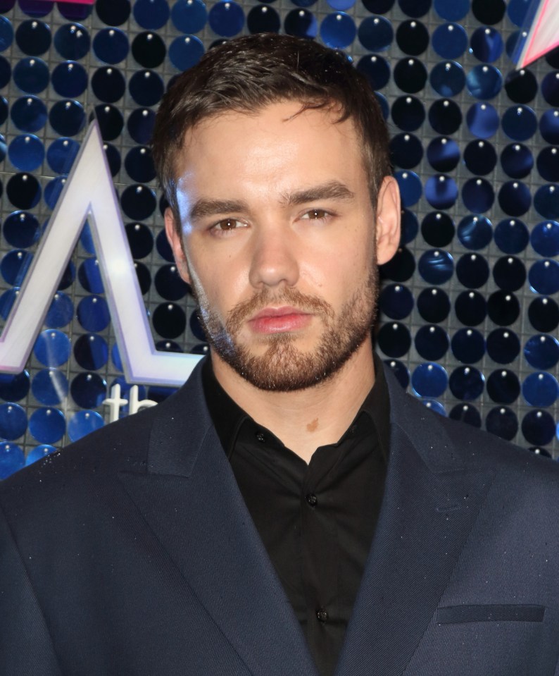 a man with a beard is wearing a blue suit and black shirt