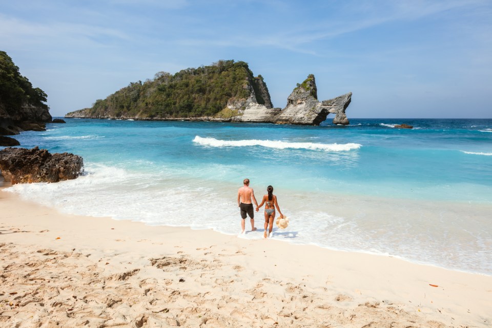 a beach with umbrellas and boats in the water