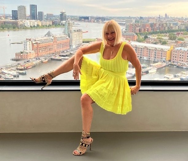 a woman in a yellow dress is sitting on a window sill