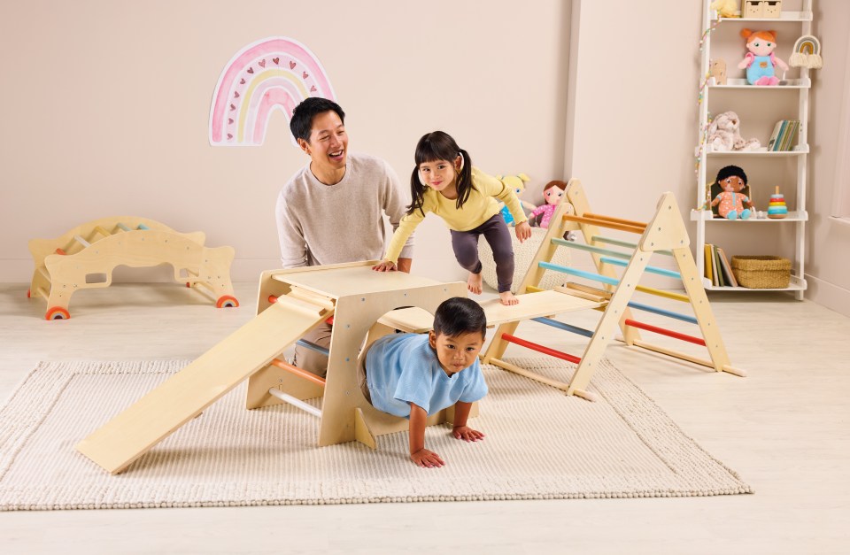 a man and two children are playing in a room with a rainbow on the wall