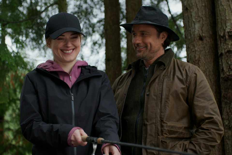 a man and a woman standing next to each other holding fishing rods