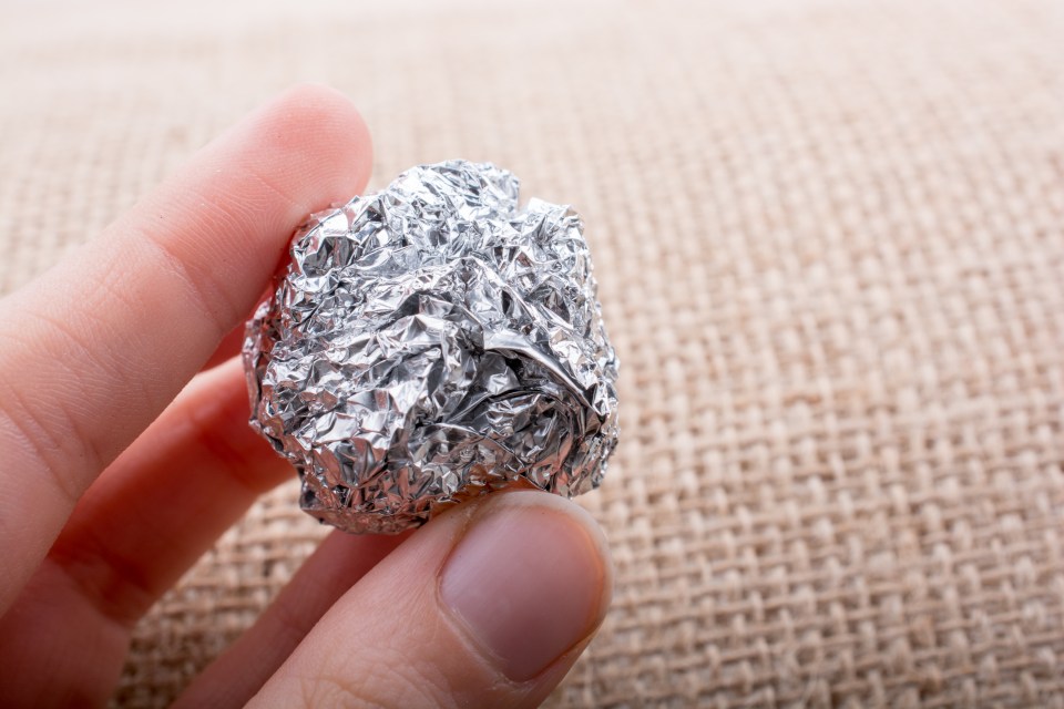 a hand is holding a piece of aluminum foil