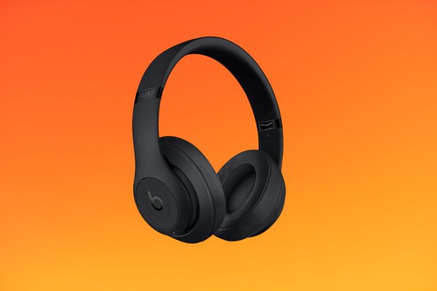 a pair of black beats headphones on an orange background