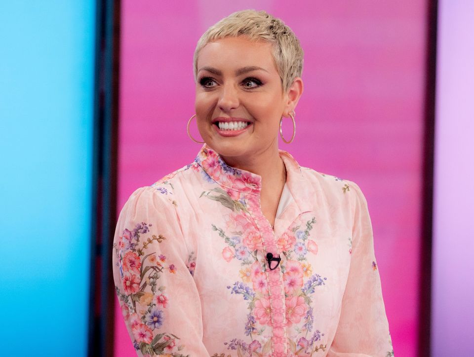 a woman wearing a pink floral shirt and hoop earrings smiles