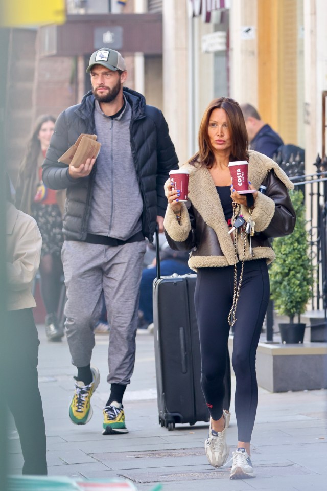 a man and woman walking down a street holding costa coffee cups