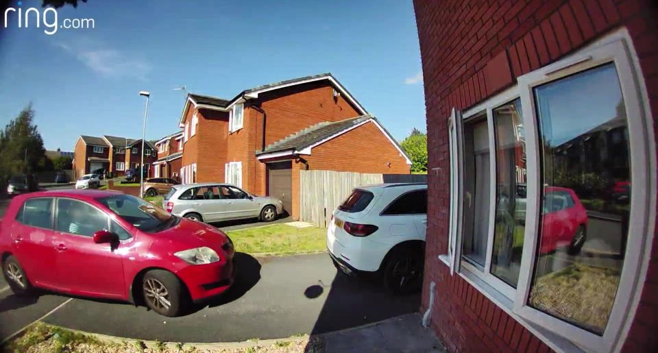 a red car is parked in front of a red brick house