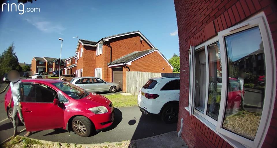 a red car is parked in front of a red brick house