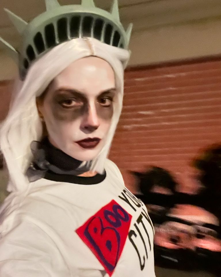 a woman in a statue of liberty costume is wearing a shirt that says boo your city