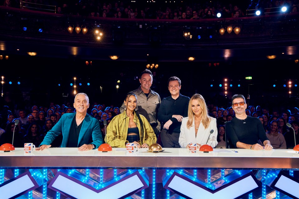 a group of people sitting at a table with a cup that says ' x factor ' on it