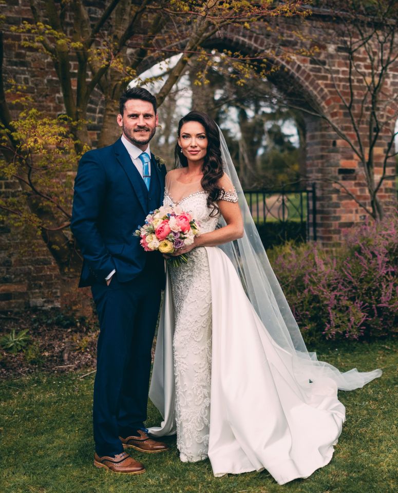 a bride and groom pose for a picture in front of a brick wall