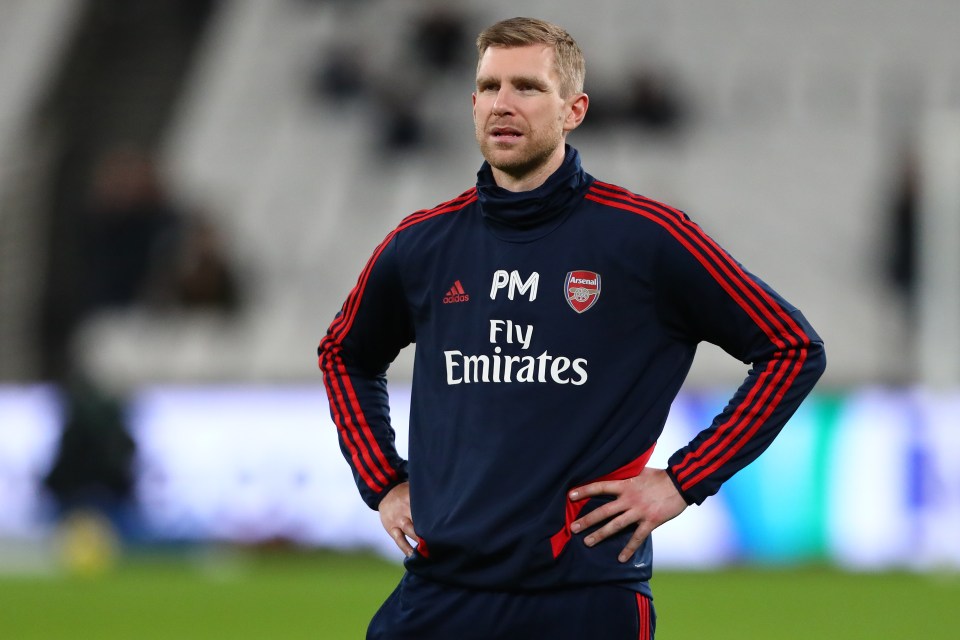 a man wearing a fly emirates shirt stands with his hands on his hips