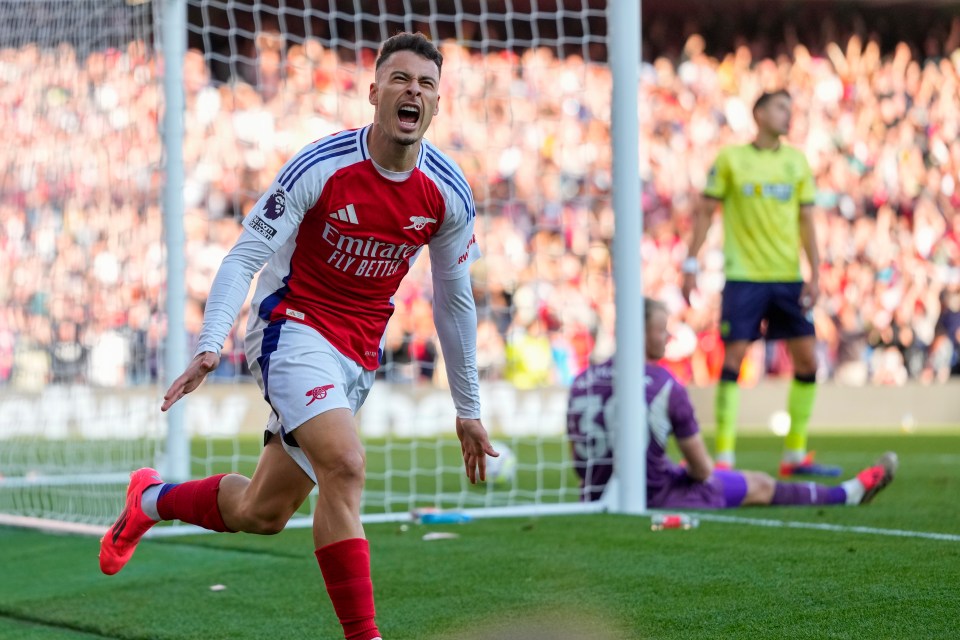 a soccer player wearing an emirates fly better jersey celebrates a goal