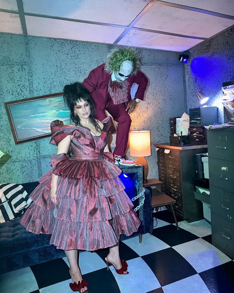 a woman in a red dress is standing next to a man in a joker costume