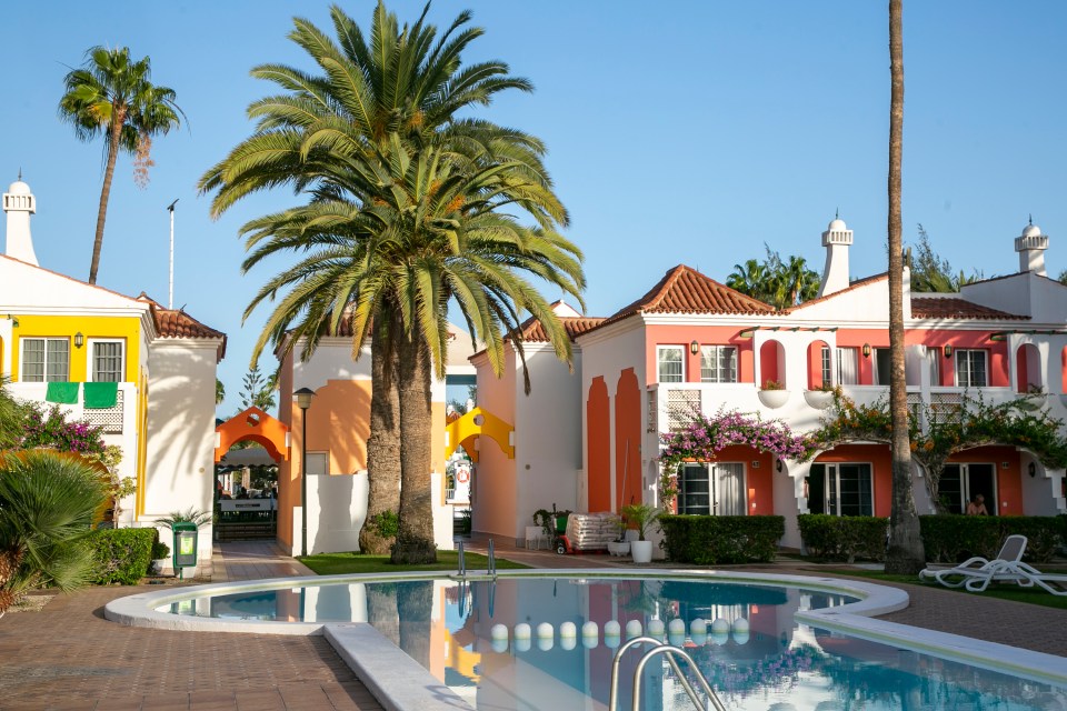 a swimming pool surrounded by colorful houses and palm trees