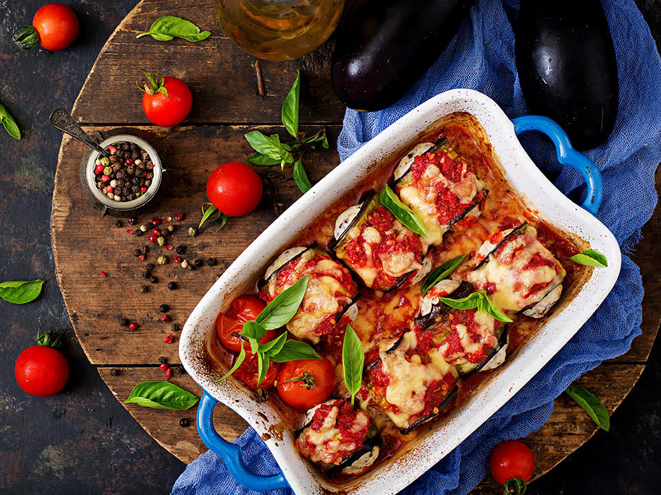 a casserole dish filled with stuffed eggplant and tomatoes