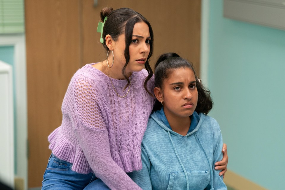 a woman in a purple sweater sits next to a girl in a blue hoodie