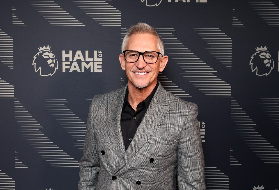 a man in a suit stands in front of a wall that says hall of fame