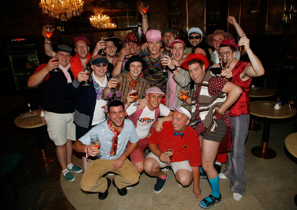 A group of men in costumes drinking beer at a party in a bar in Prague