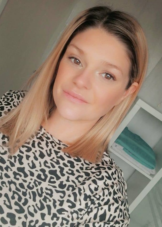 a woman wearing a leopard print shirt smiles for the camera