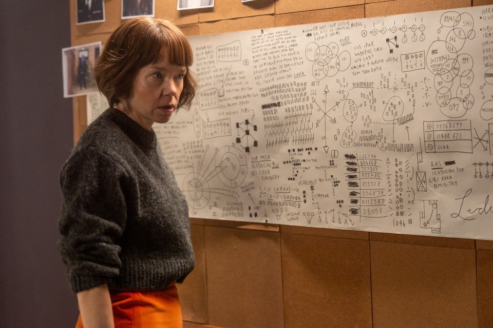 a woman stands in front of a large white board with a lot of writing on it