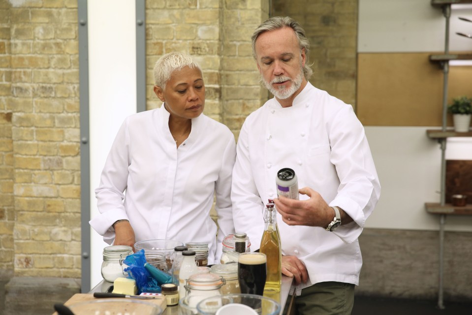 a man and a woman standing next to each other looking at a bottle