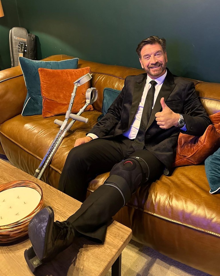 a man with crutches and a knee brace gives a thumbs up