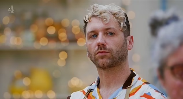 a man with curly hair and a beard is wearing a colorful shirt and apron .