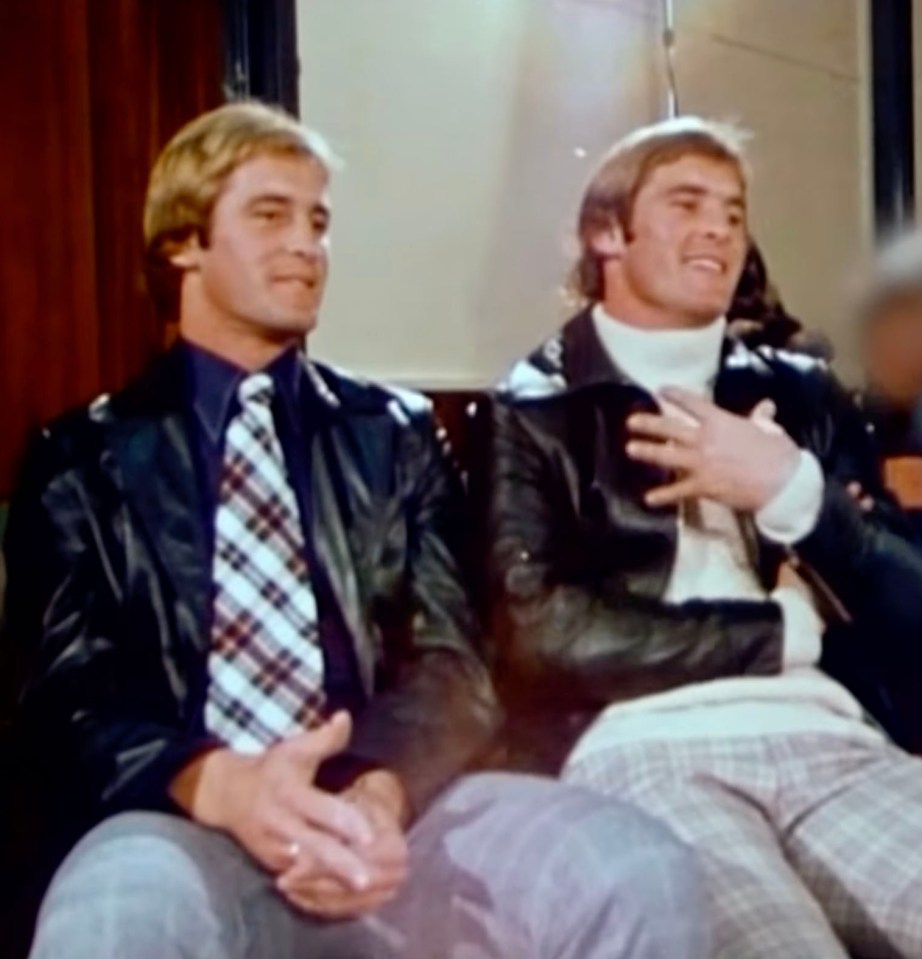 two men are sitting next to each other and one is wearing a leather jacket