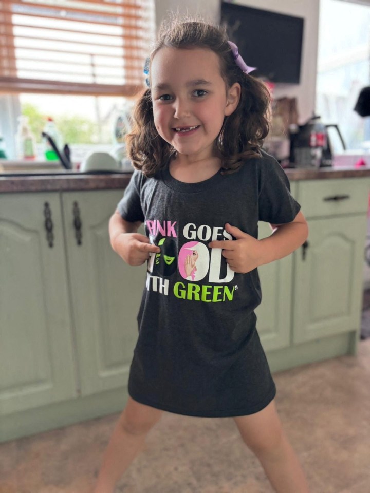 a little girl wearing a shirt that says " pink goes 4th green "