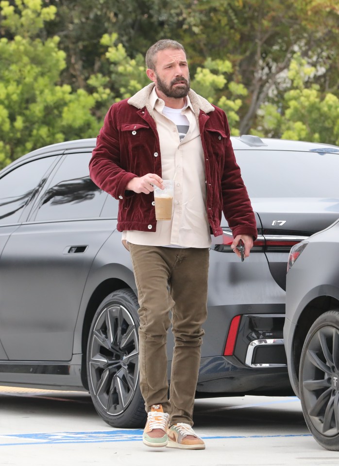 a man in a red jacket is holding a cup of coffee