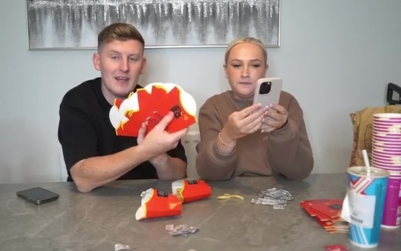 a man and a woman sit at a table playing monopoly