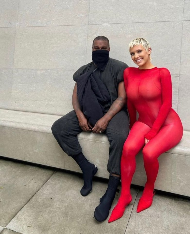 a man in a black mask sits next to a woman in a red bodysuit