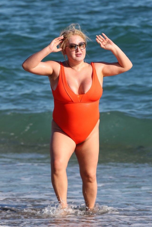 a woman in an orange swimsuit is standing in the ocean