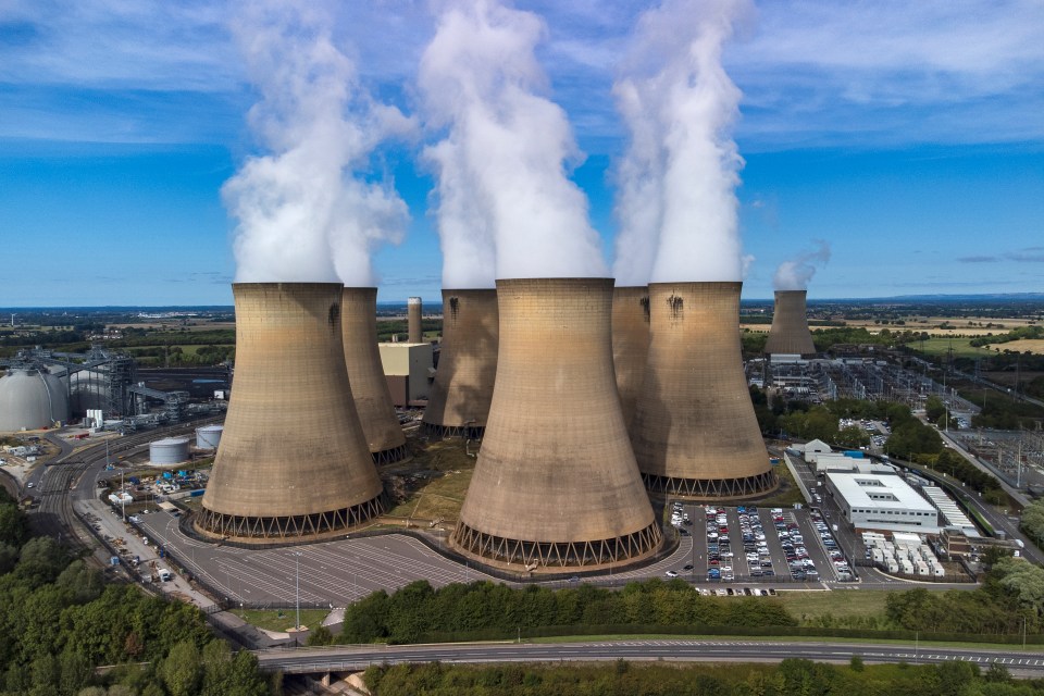 an aerial view of a power plant with smoke coming out of the cooling towers