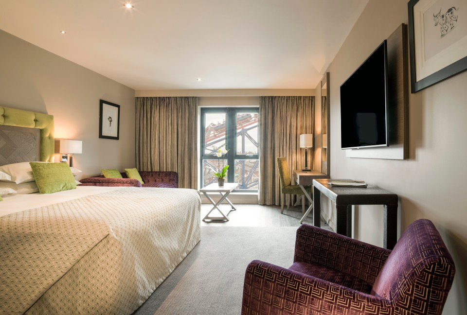 a hotel room with a large bed and a purple chair