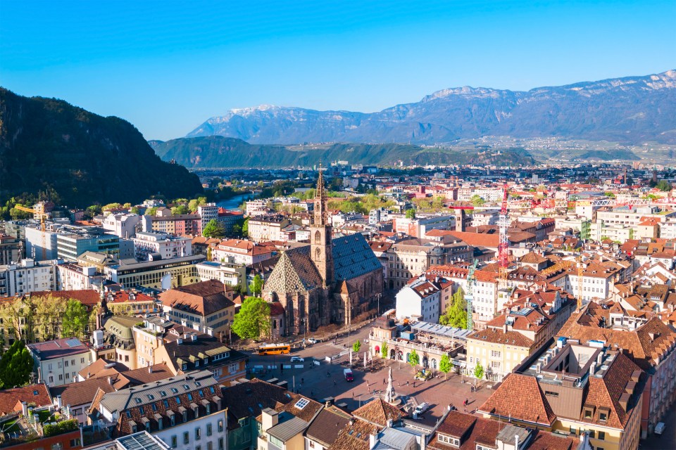 a ferris wheel is in the foreground of a city with mountains in the background