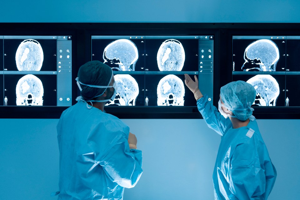 Surgeons looking at magnetic resonance imaging (MRI) brain scans during brain surgery.